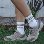 Person wearing hiking boots and white socks with red text on grass